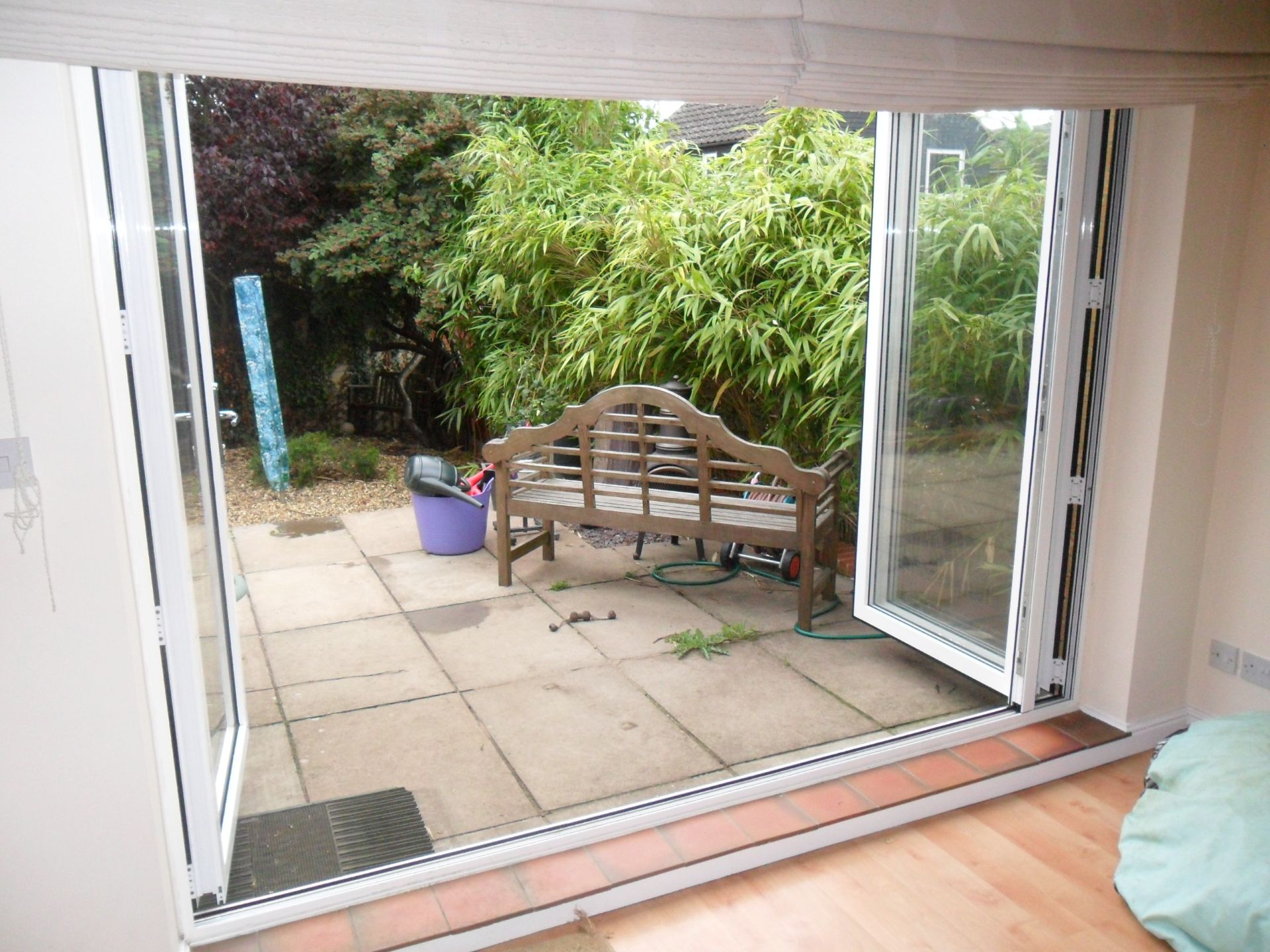 White bi-fold doors folded open from a room onto a stone patio and garden