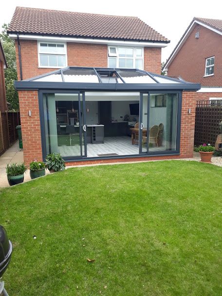 Grey aluminium orangery with bi-fold doors onto a lawn