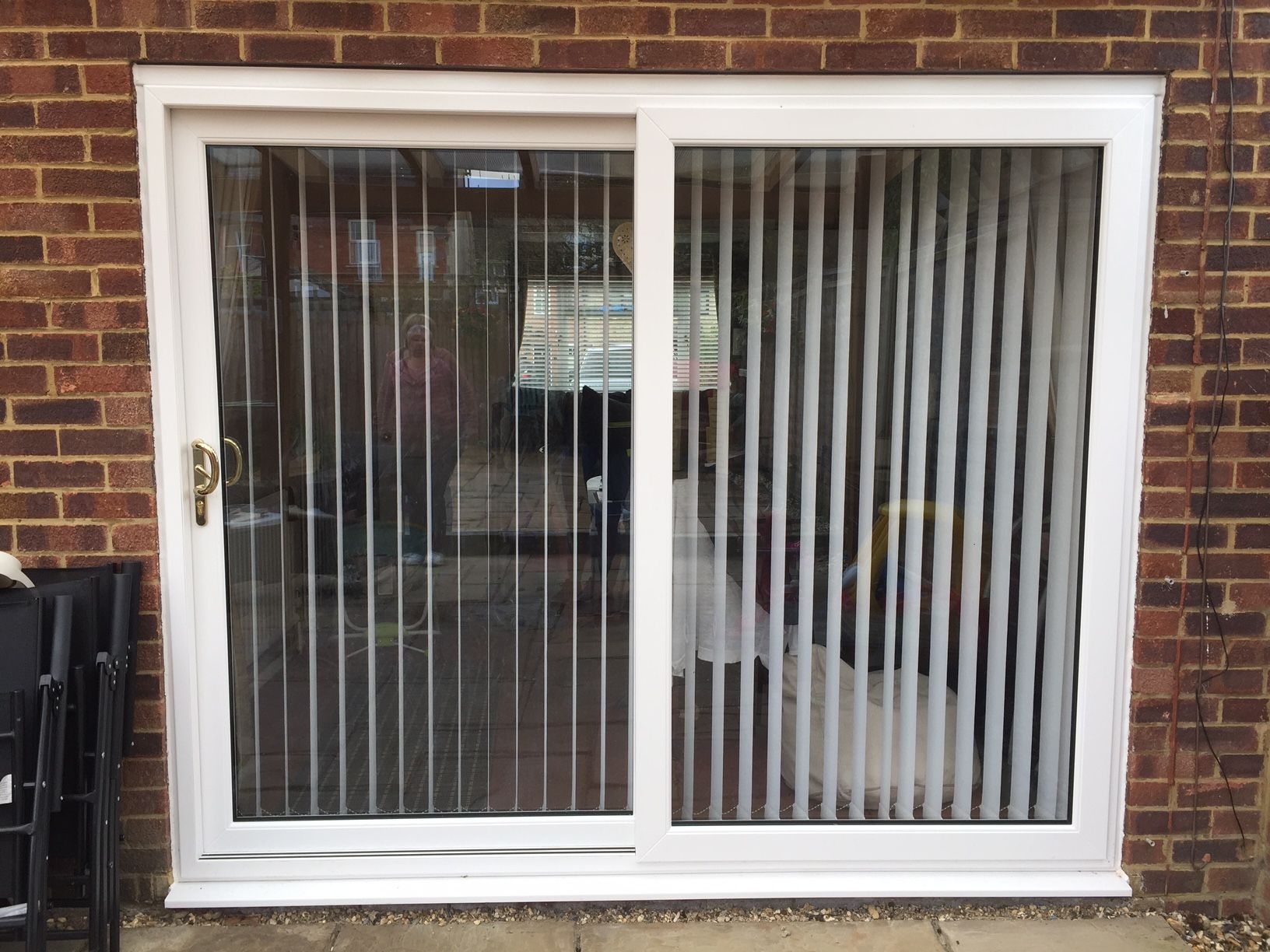 White sliding patio doors on a brick bungalow with a wisteria-covered terrace